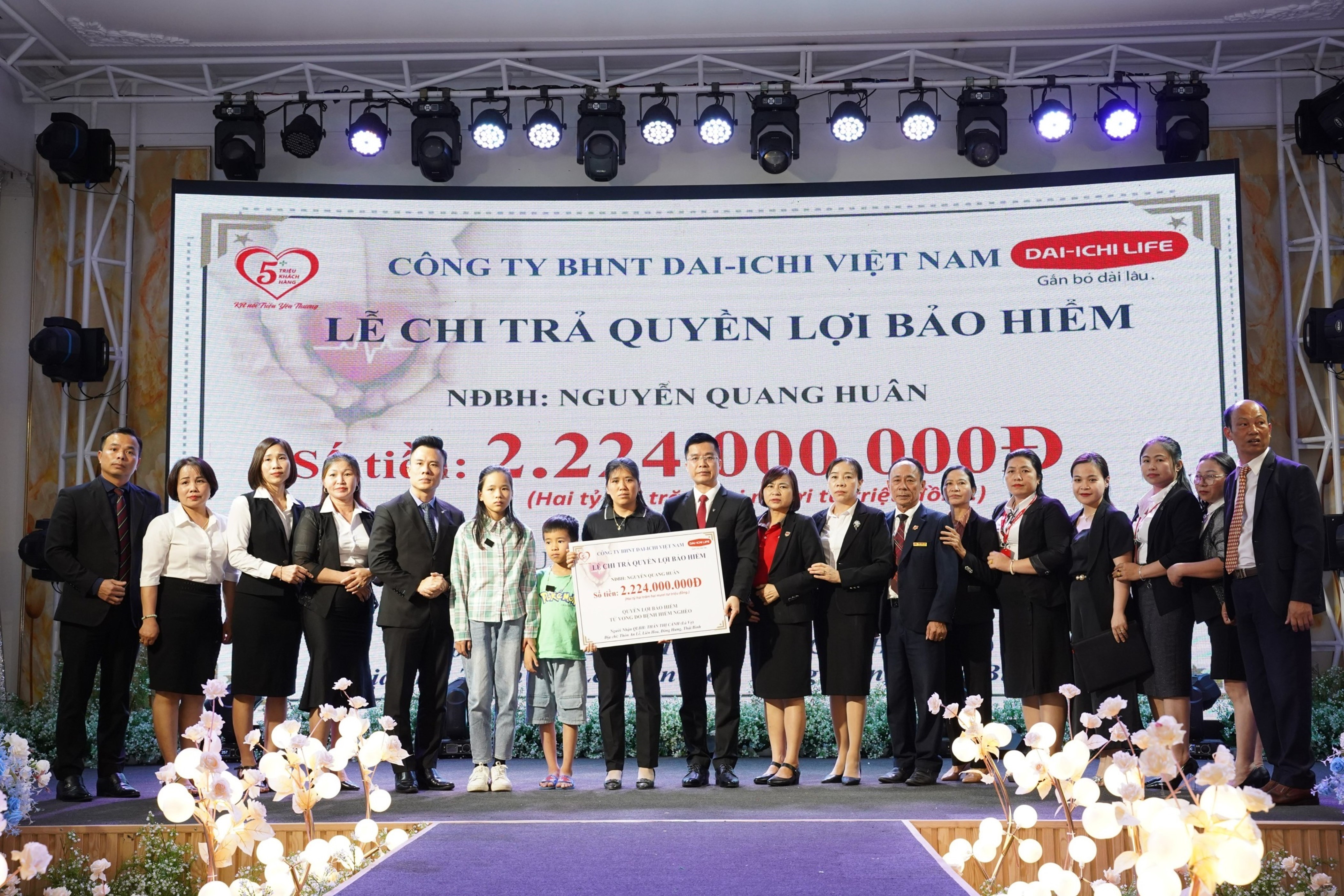 Bà T.T.C, vợ của khách hàng N.Q.H nhận tấm séc tượng trưng số tiền chi trả quyền lợi bảo hiểm tại buổi lễ.
